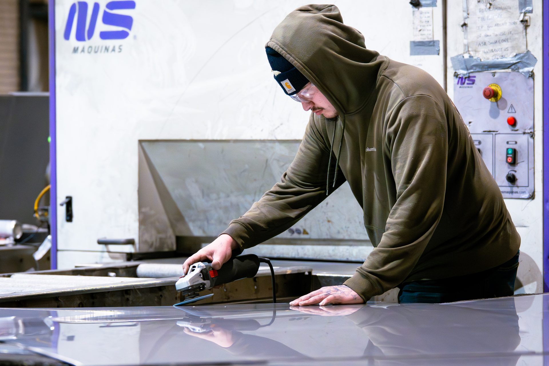 Worker sanding stainless steel with orbital sander