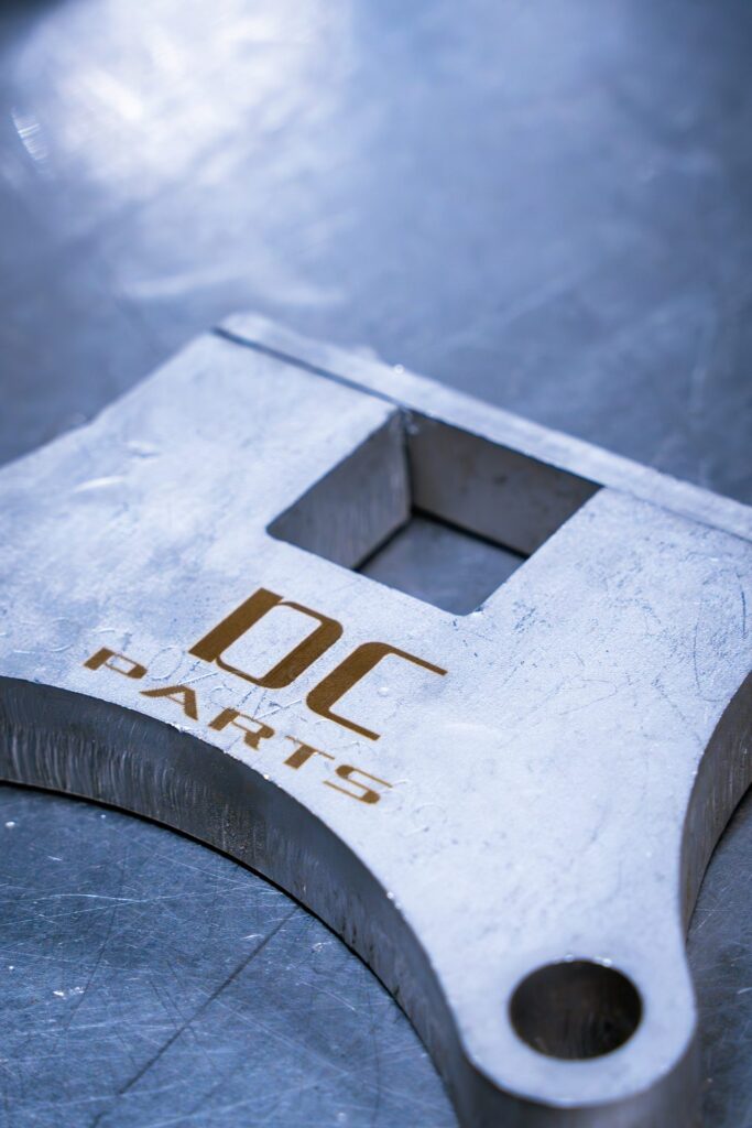 Laser-engraved DC Parts logo on precision-machined metal component